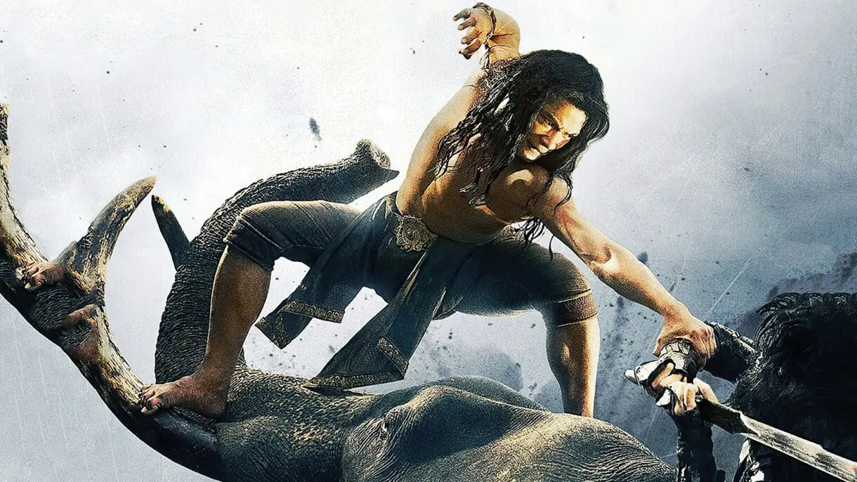 Un hombre subido sobre un tronco con una espada en Ong Bak II